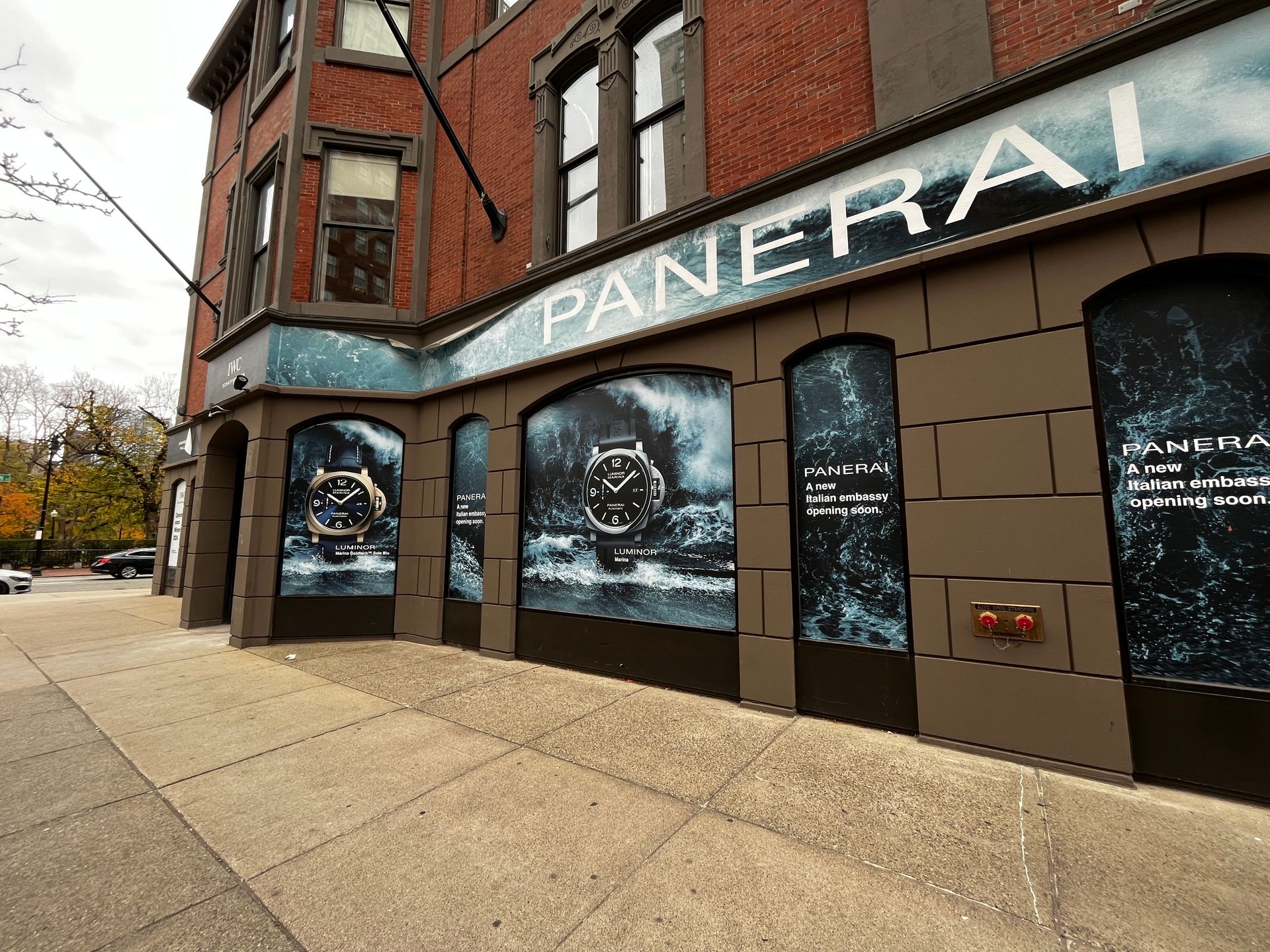 Panera Bread storefront on a city corner with blue window ads and brick facade