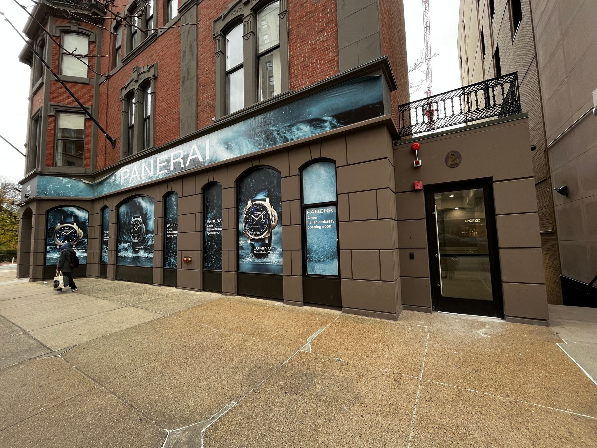 Brick storefront with blue awning and posters along a sidewalk in a city street