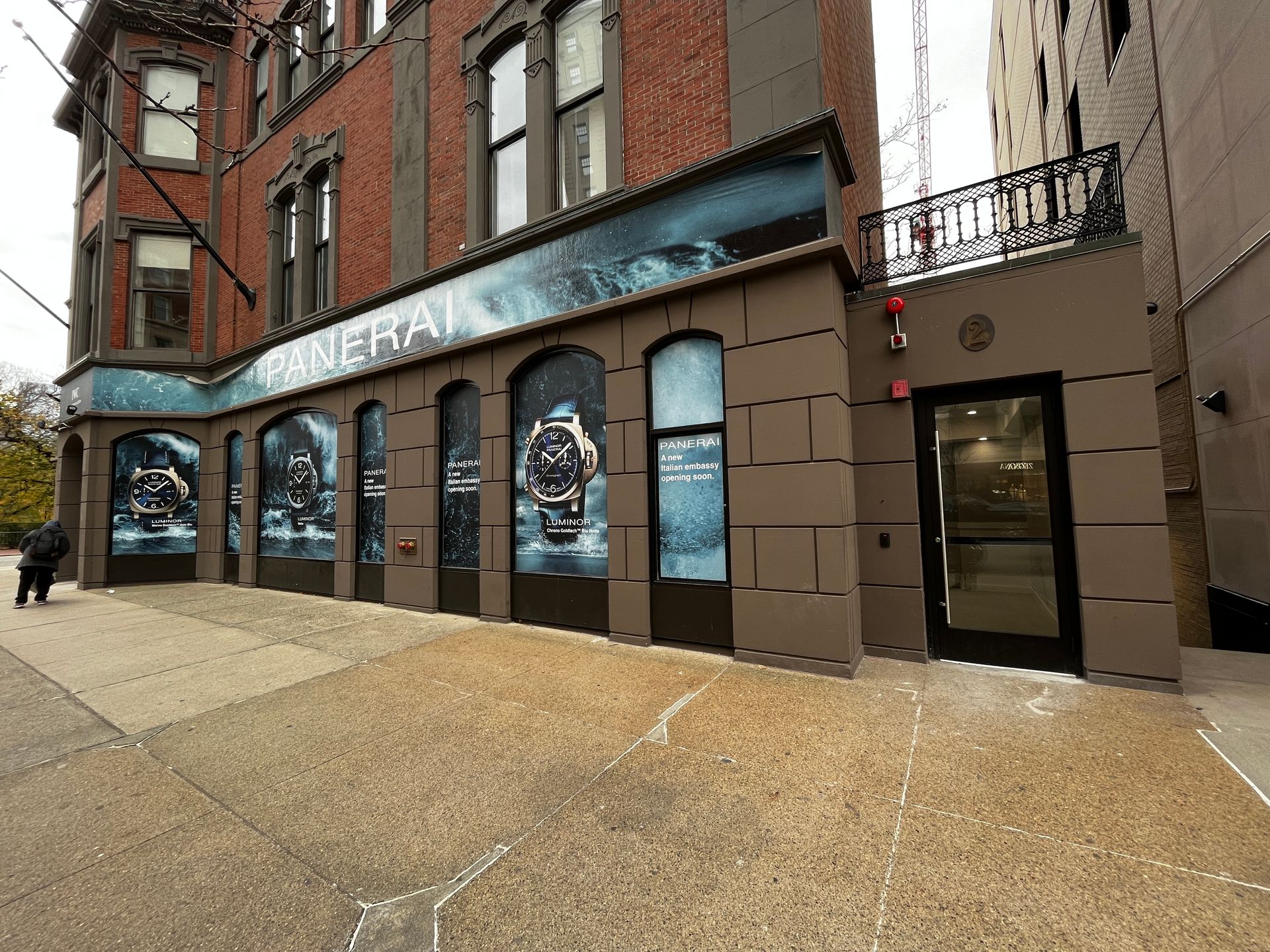 Storefront with blue-lit windows on a brick sidewalk beside a red brick building