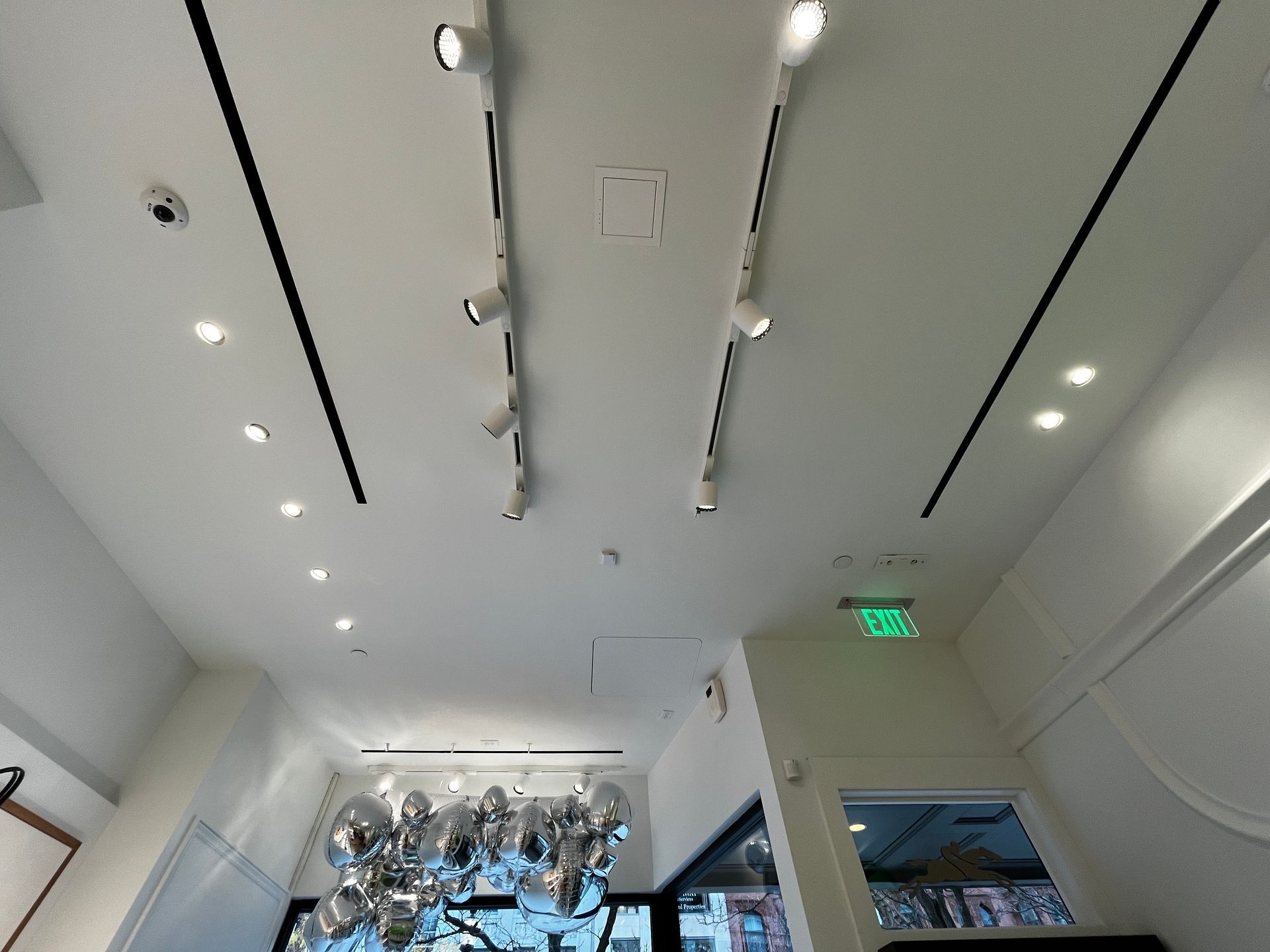 Modern gallery interior with white ceiling lights and silver balloon decorations near the back wall
