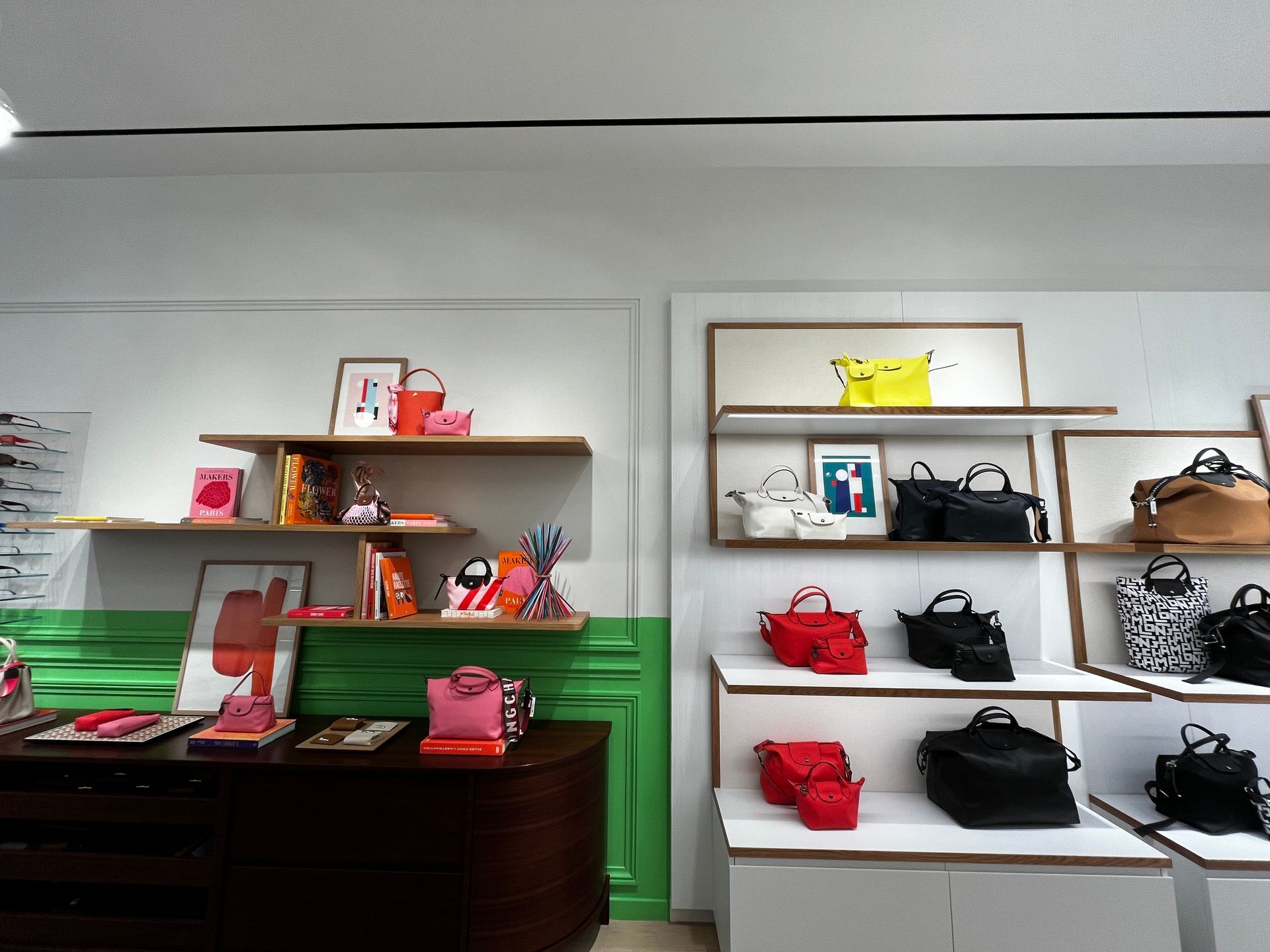 Store display of handbags and accessories on shelves above green-paneled counters