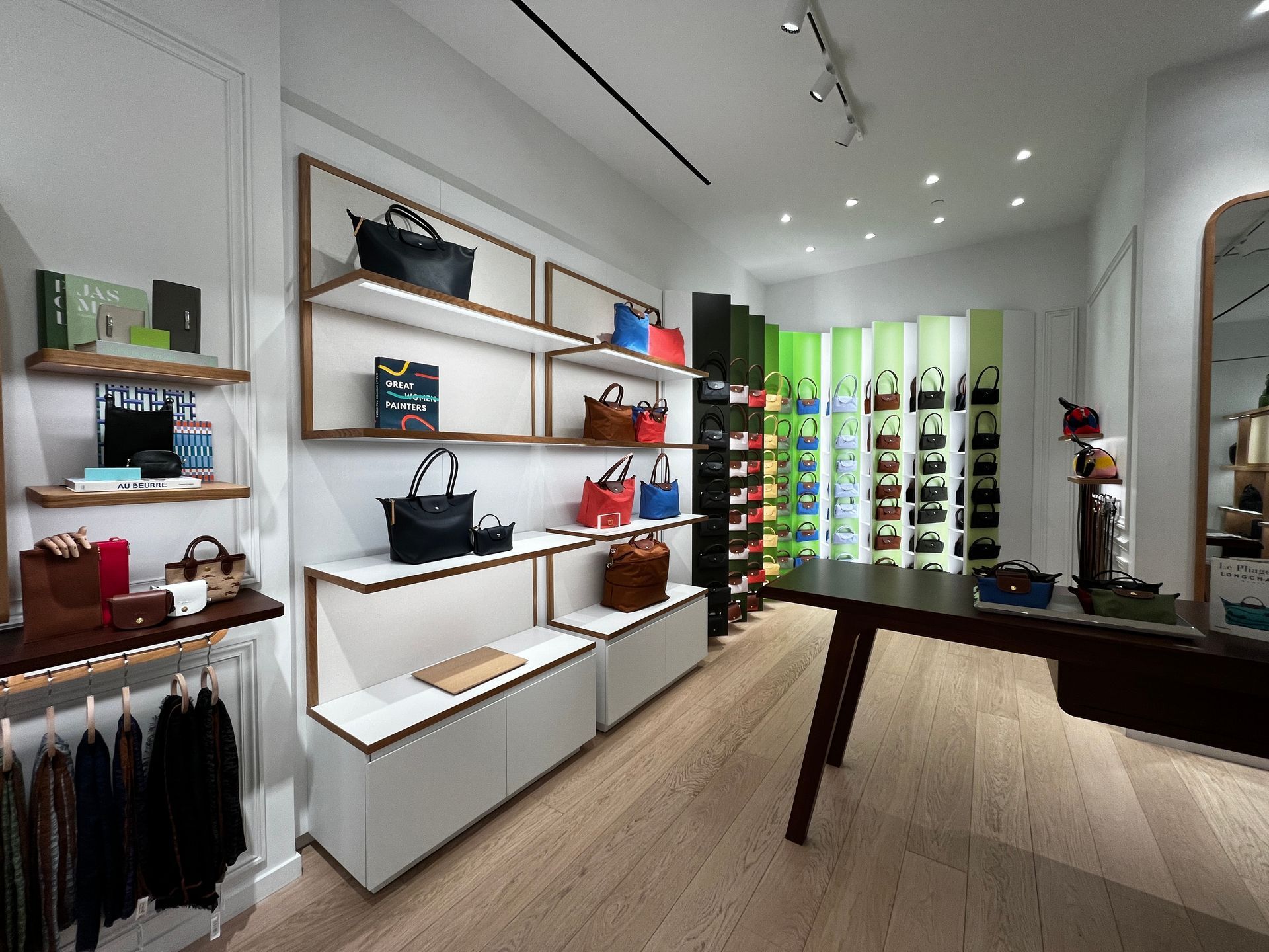 Modern boutique store interior with wall shelves, clothing racks, and a pool table-like display table