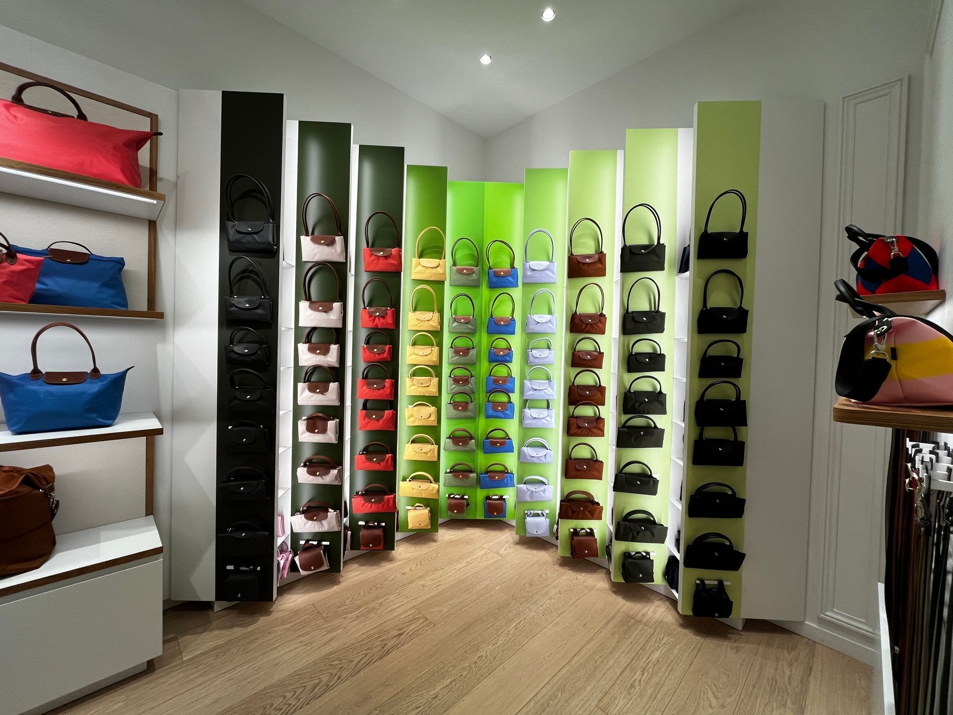 Bright boutique display with colorful handbags arranged on curved wall shelves in a modern white room