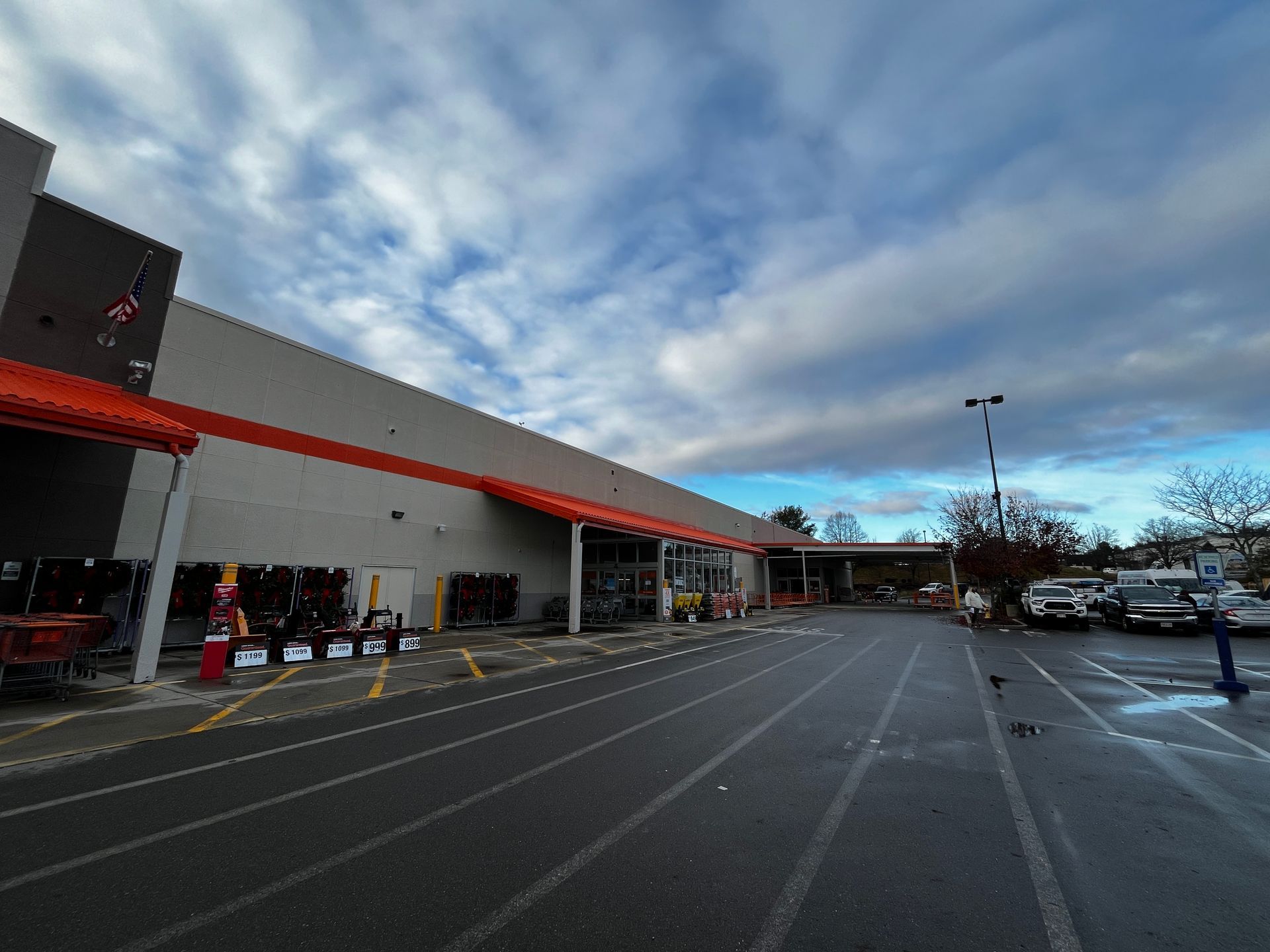 Wide outdoor parking lot beside a storefront with red awning and cloudy sky