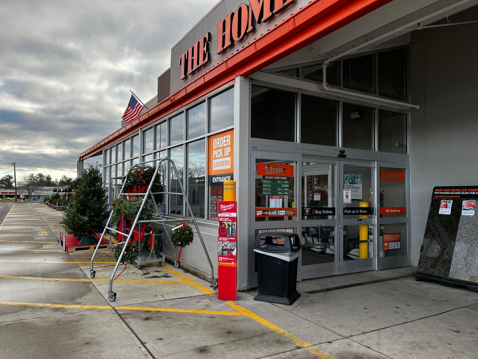 Home Depot storefront with shopping carts, entrance doors, and cloudy parking lot