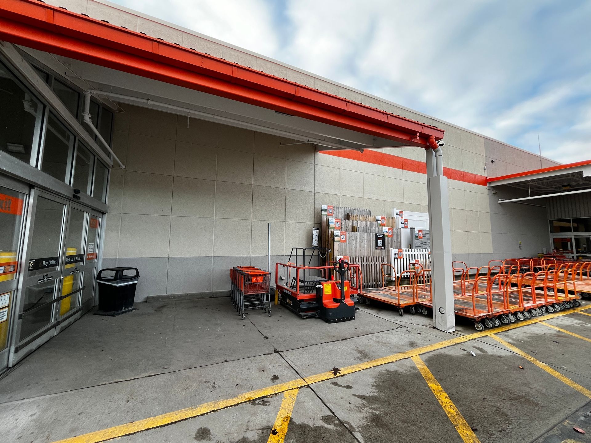 Covered loading dock with orange carts and equipment along a concrete wall