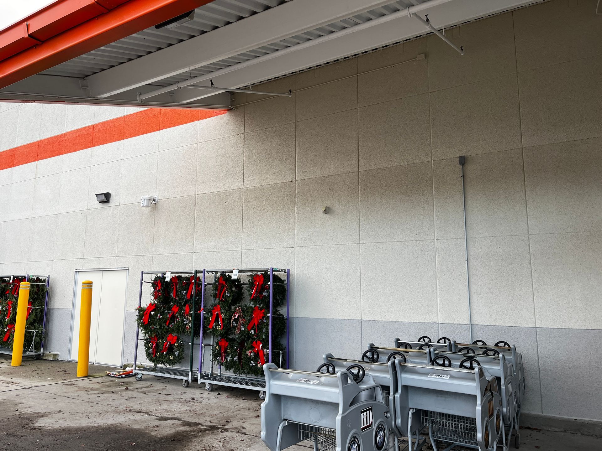 Industrial wall with metal carts and hoses under a canopy, with red and black equipment racks nearby