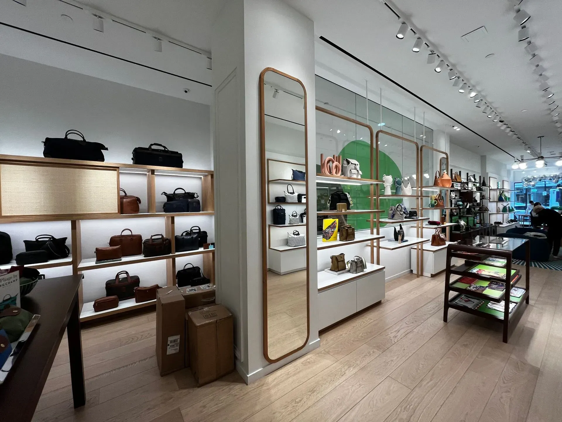 Modern retail store interior with shelves of handbags, shoes, and accessories along a bright aisle
