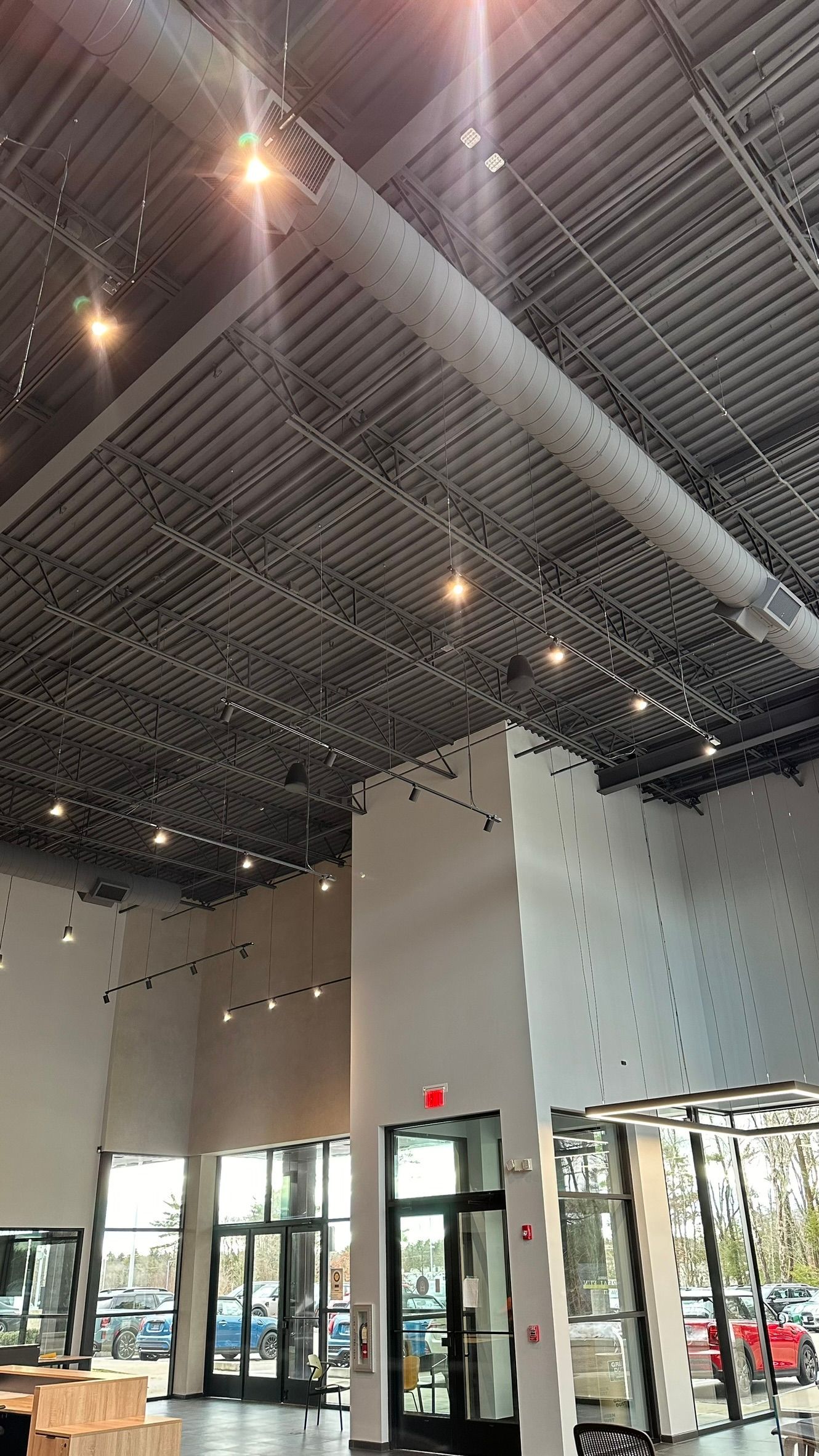 Bright store interior with high industrial ceiling, glass doors, and hanging lights
