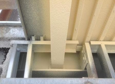 White metal beam supports under a corrugated roof, viewed from below