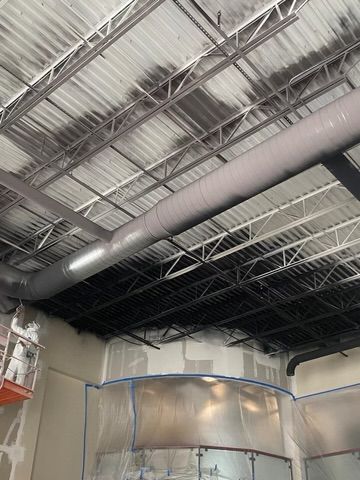 Ceiling of an industrial interior with exposed ducts, pipes, and metal framing under construction