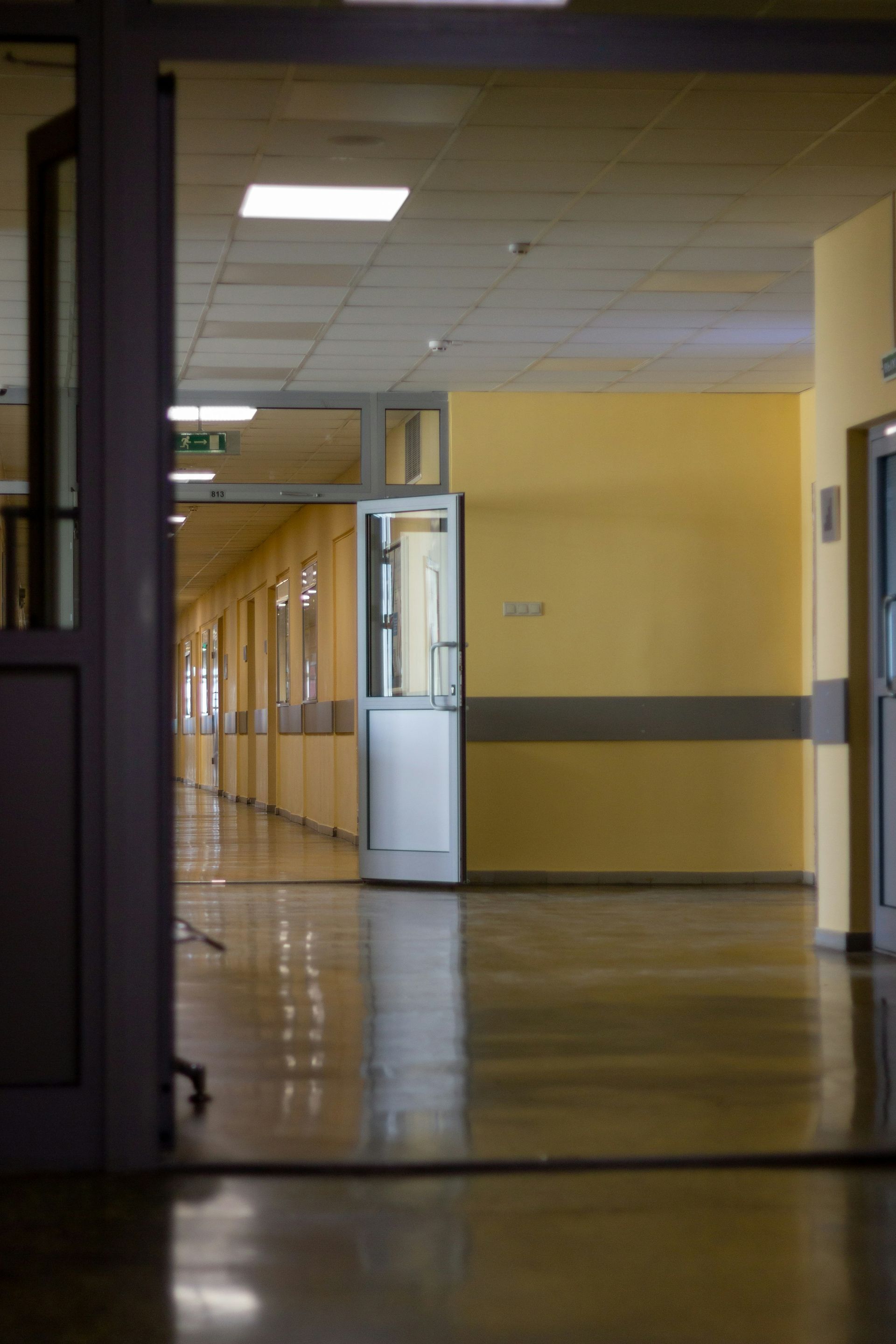 Empty yellow hallway with polished floor and fluorescent ceiling lights