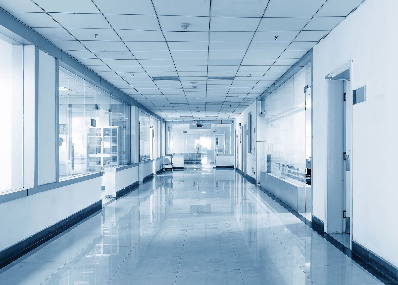 Empty, bright hospital hallway with glossy floors and doors along both sides