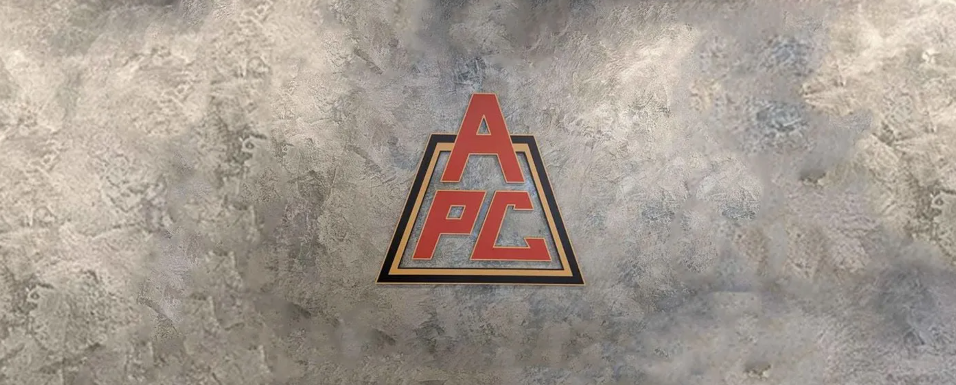 Red APC logo on a gray concrete wall