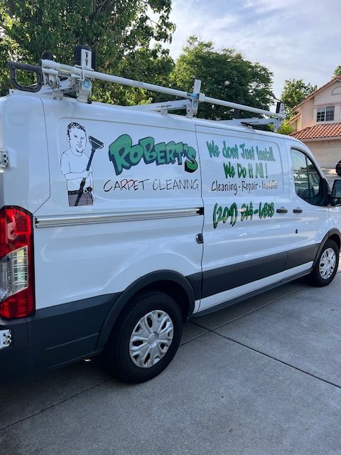 A white carpet cleaning van is parked in a driveway.
