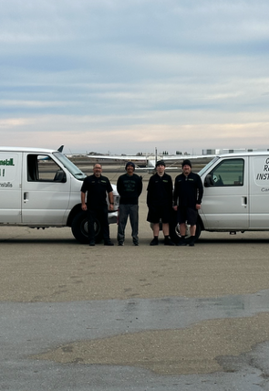 A group of men are standing in front of a white van that says ' emerald ' on the side