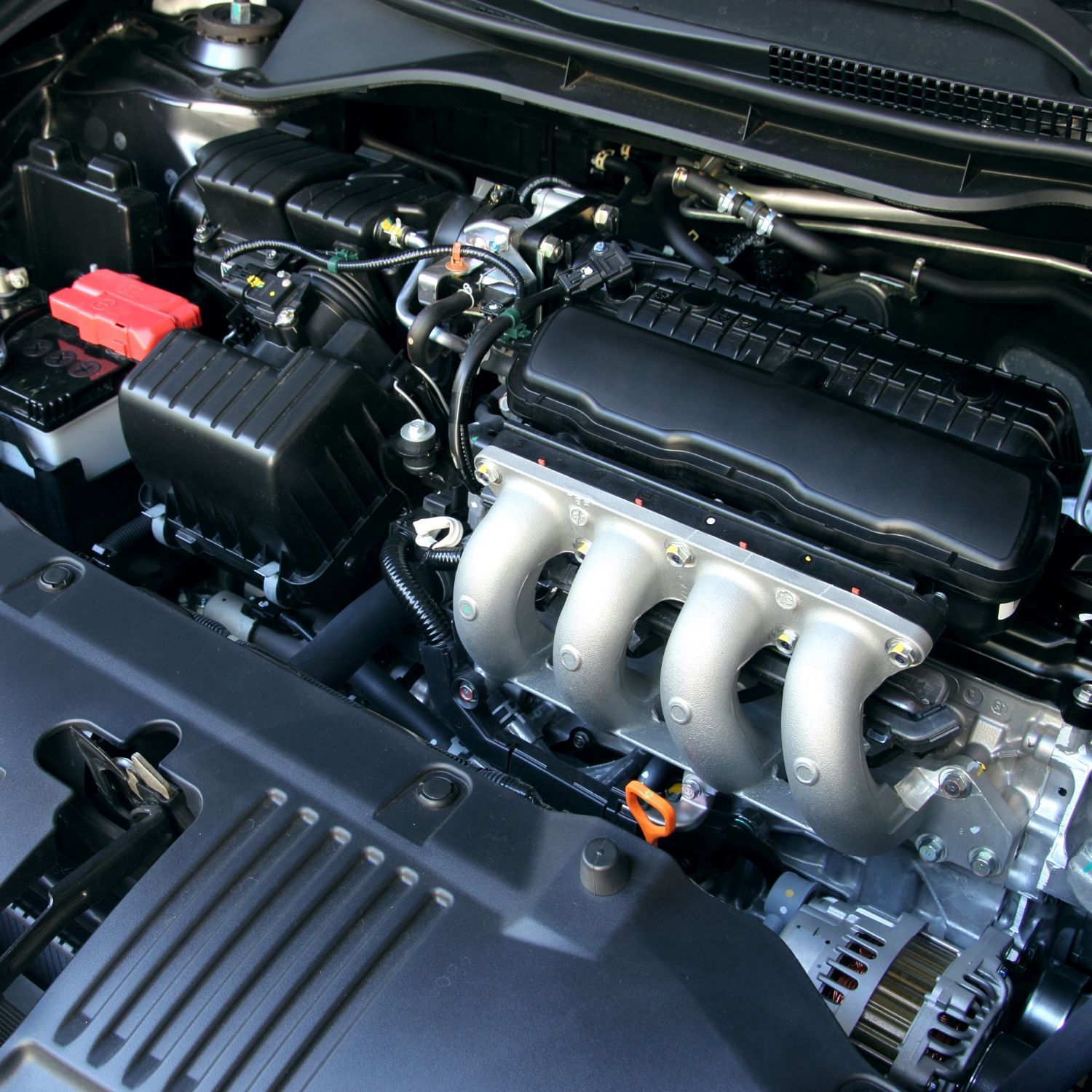 A clean, high-angle view of an internal combustion car engine with silver intake manifolds and black components.