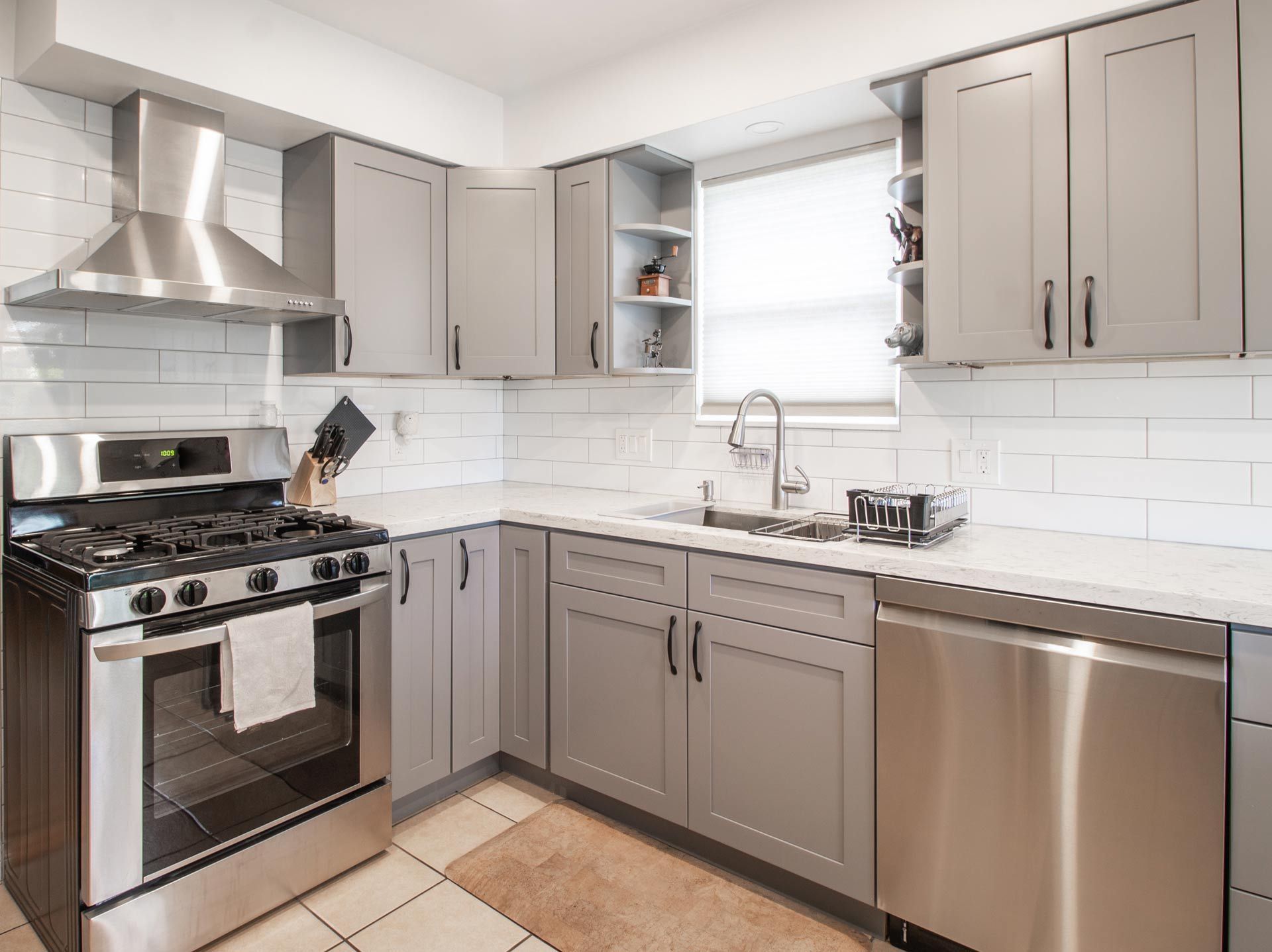 A kitchen with white cabinets , stainless steel appliances , hardwood floors and a large island.