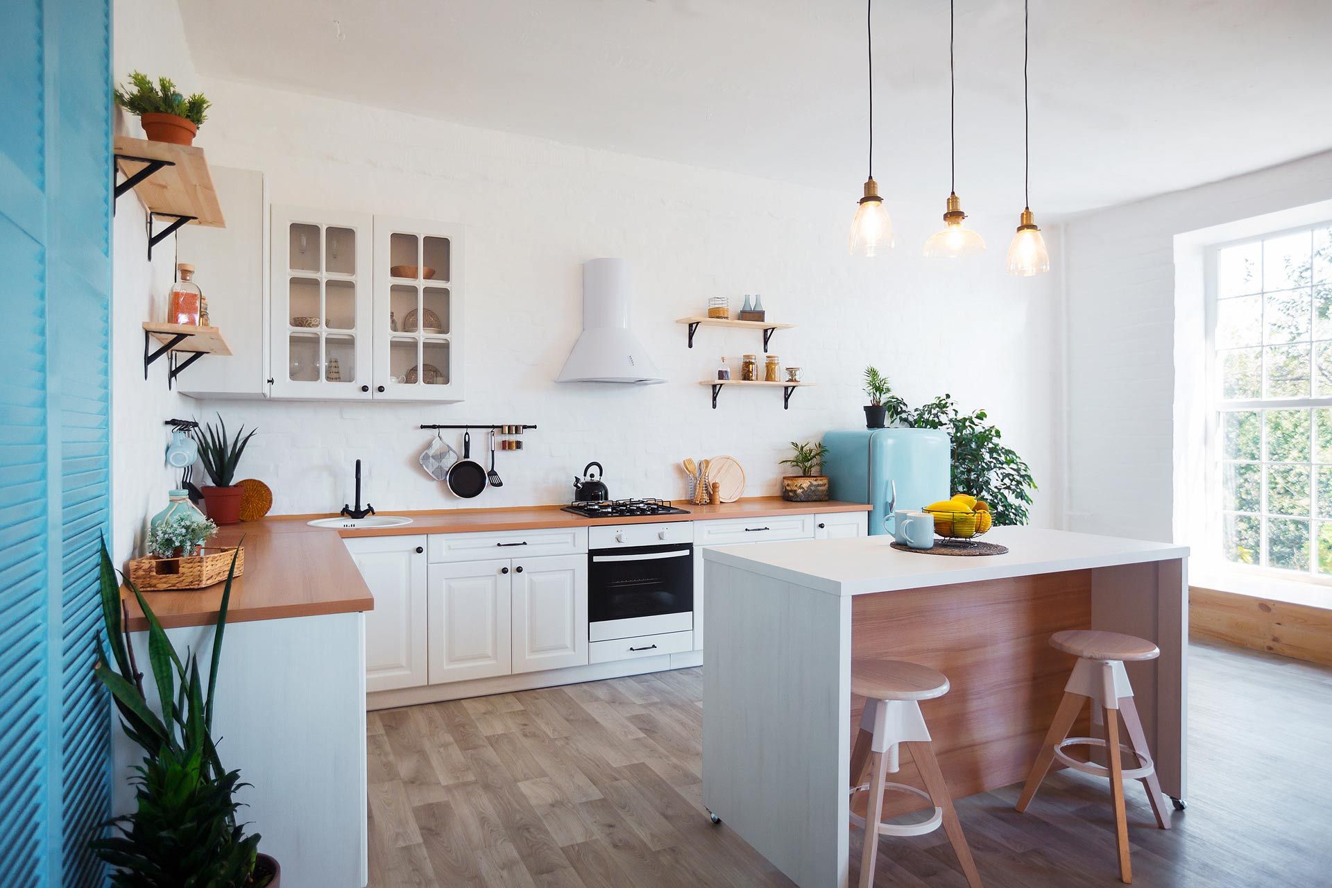 Bright modern kitchen with white cabinets, wood counters, island stools, and hanging pendant lights