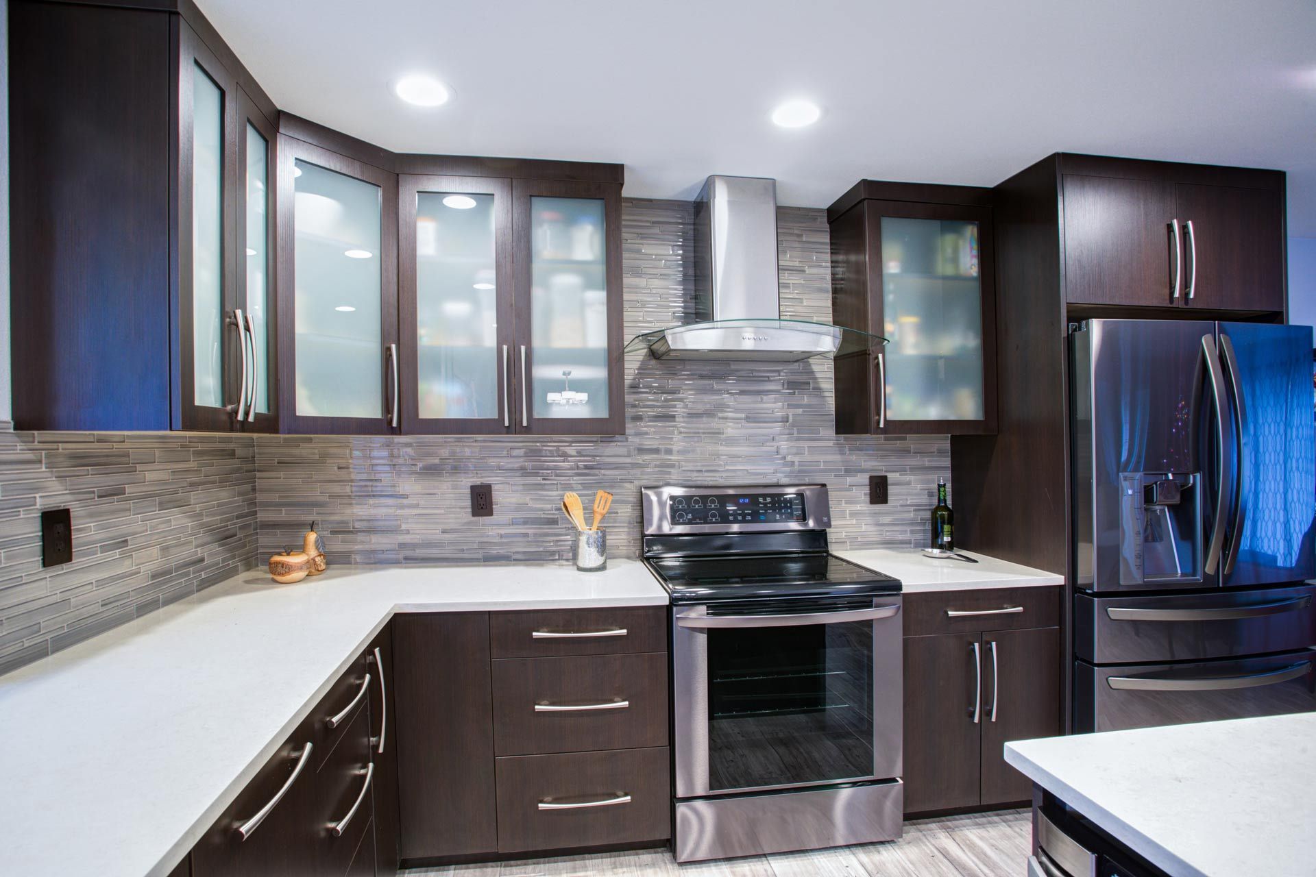 Modern kitchen with dark wood cabinets, stainless steel appliances, and light countertops