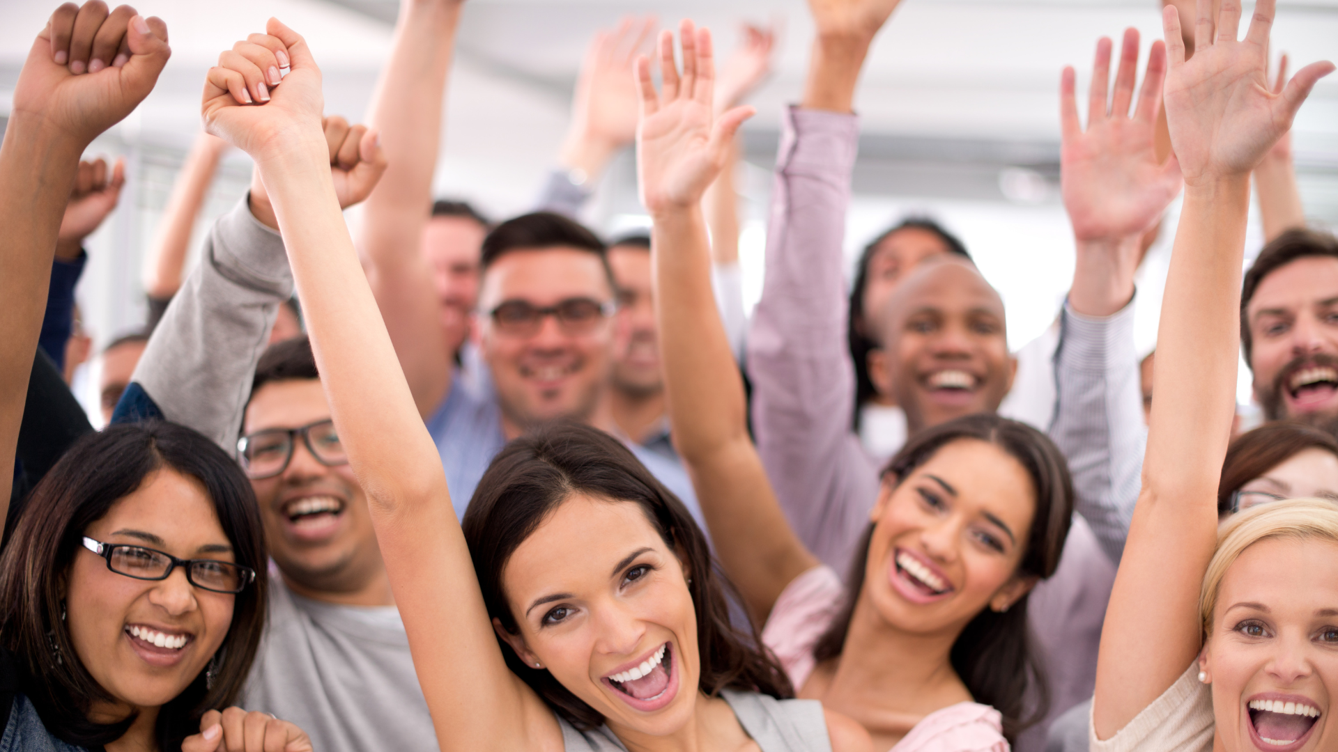 Smiling group raising hands in a bright office setting