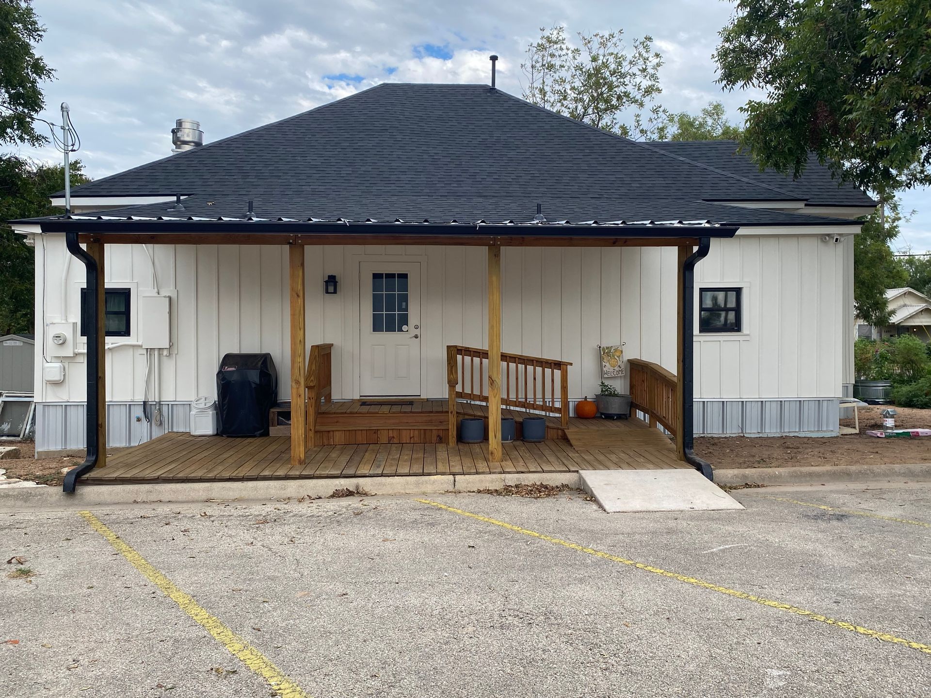 A white house with a black roof and a porch.