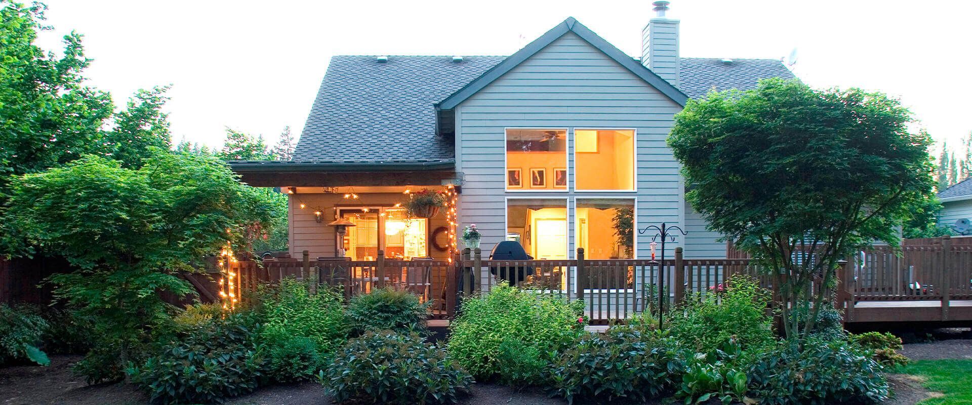 A house with a large deck and lots of windows is lit up at night.
