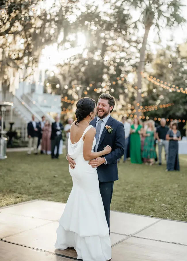 Bride and groom dancing at an outdoor wedding reception under string lights