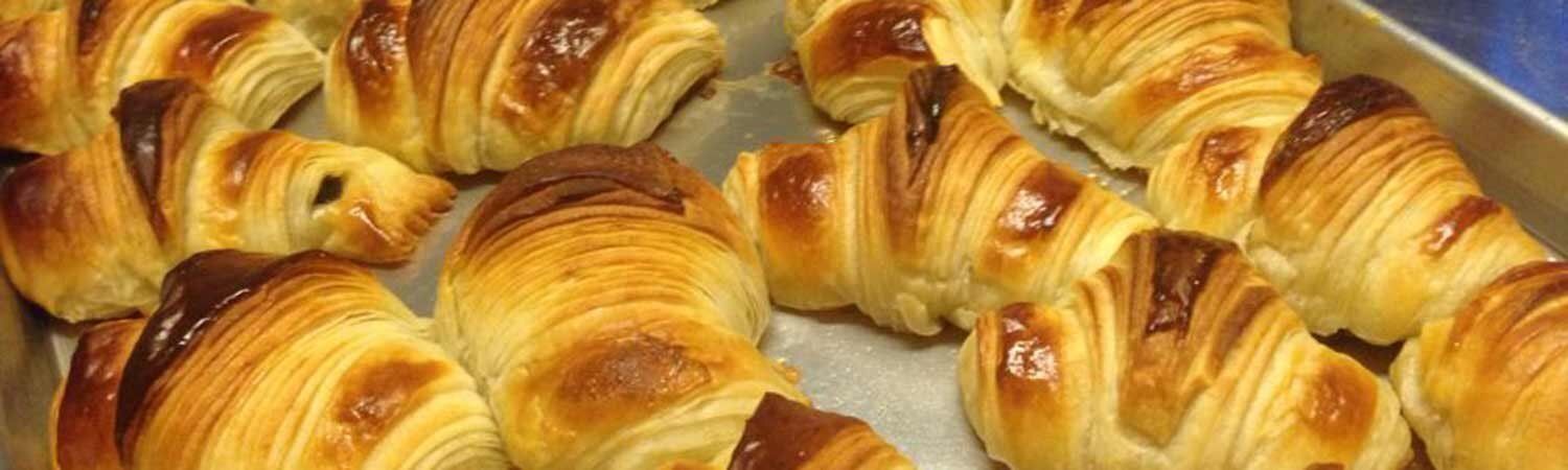 Golden-brown croissants stacked together in a close-up bakery display