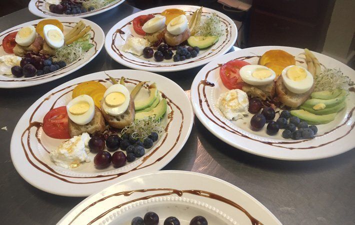 Plates of assorted desserts with sliced fruit, cookies, and cream cups on a table