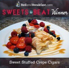 Sweet stuffed crepe cigars topped with berries and syrup on a plate, BedandBreakfast.com winner badge