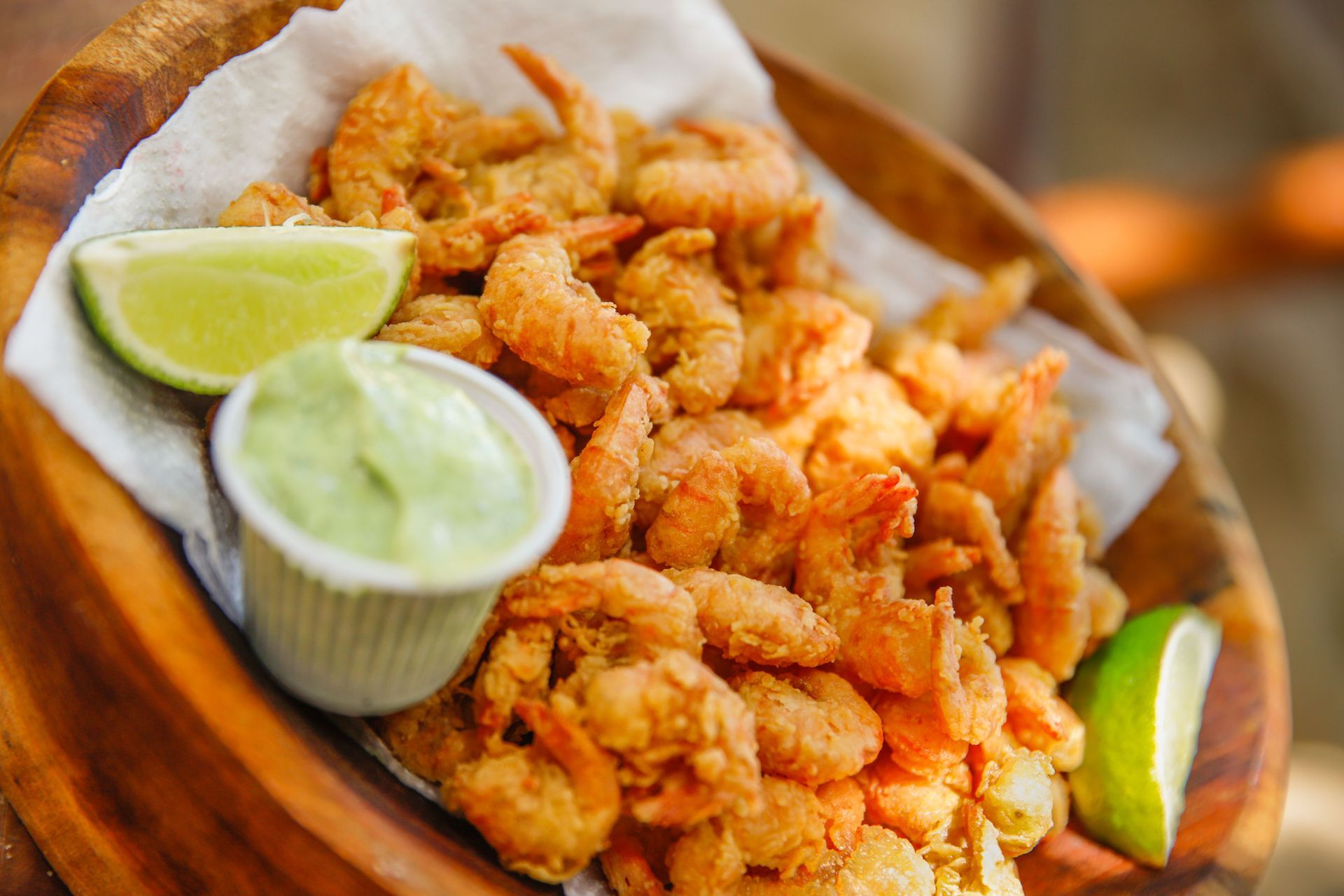 Fried shrimp served on a wooden platter with lime wedges