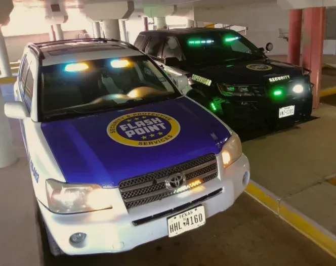 Two parked police SUVs, one white and blue, one black with green lights, in a garage bay