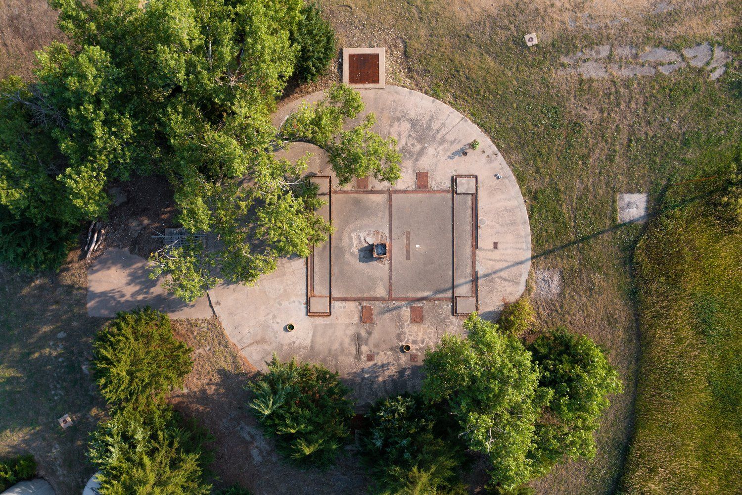 Aerial view of a concrete military gun emplacement surrounded by grass and trees.