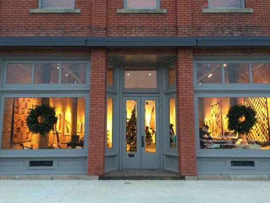 The front of a brick building with a christmas tree in the window