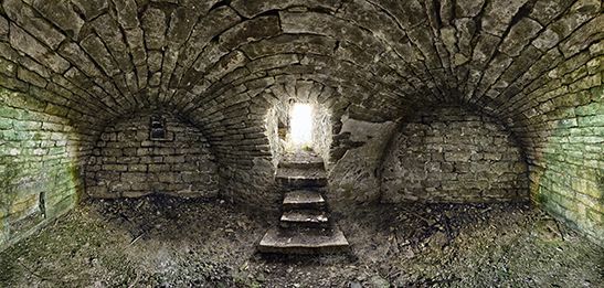 Stone tunnel with steps leading to a bright light at the end.