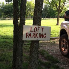A white truck is parked in front of a sign that says loft parking.