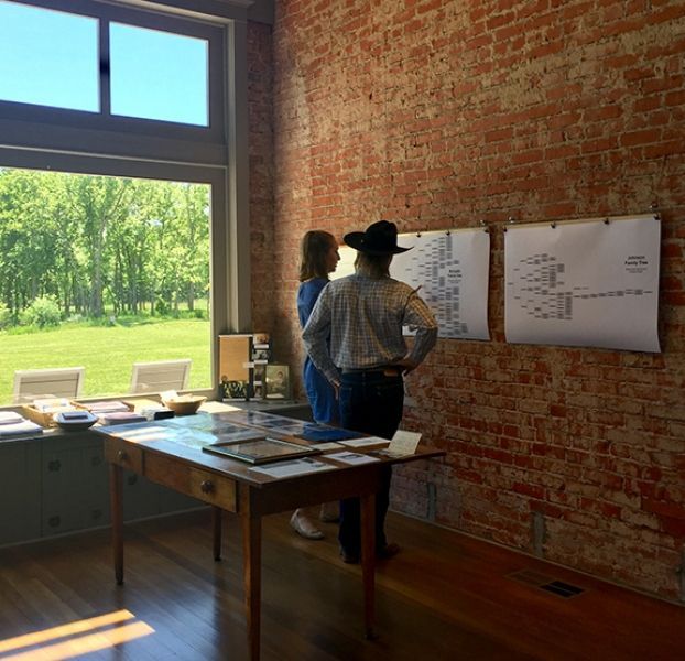 Two people standing in front of a brick wall looking out a window