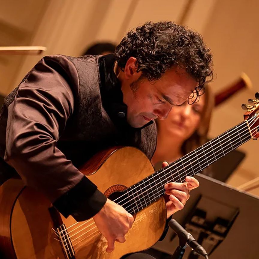 a person with dark curly hair plays guitar