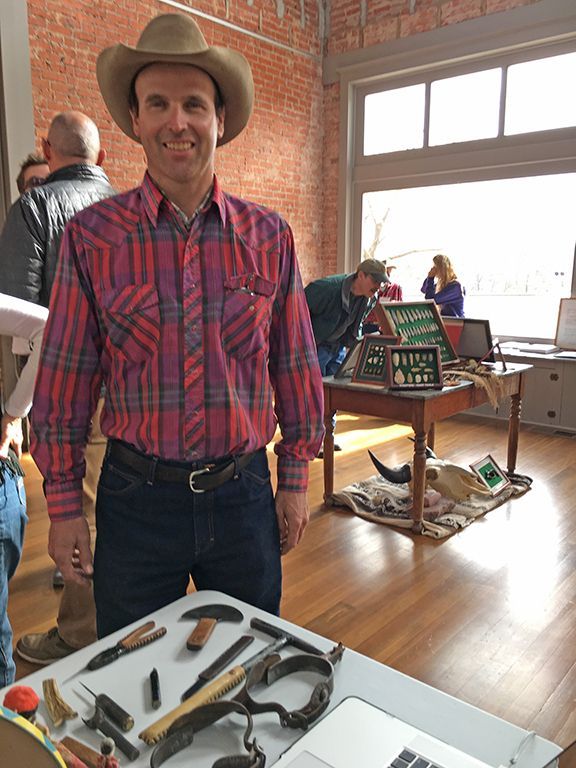 A man wearing a cowboy hat is standing in front of a table with tools on it.