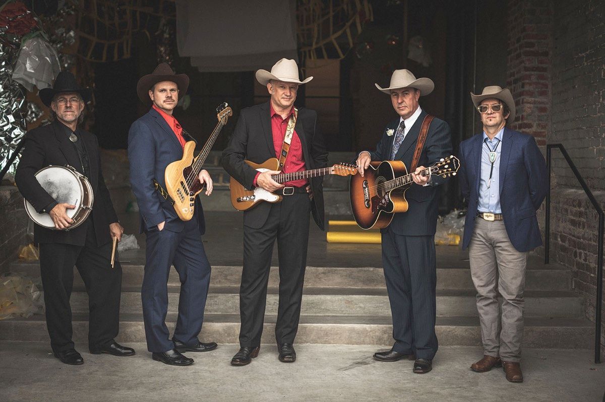 A group of men in cowboy hats are standing next to each other holding guitars.