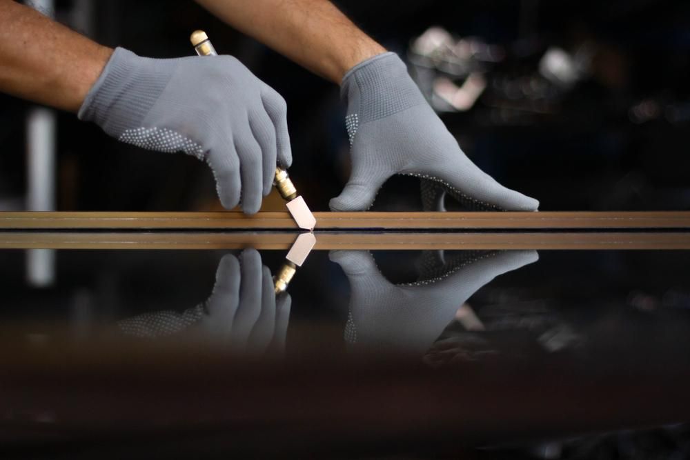 A Person Is Cutting a Piece of Glass with A Glass Cutter — Grainger Windows & Doors in Alstonville, NSW