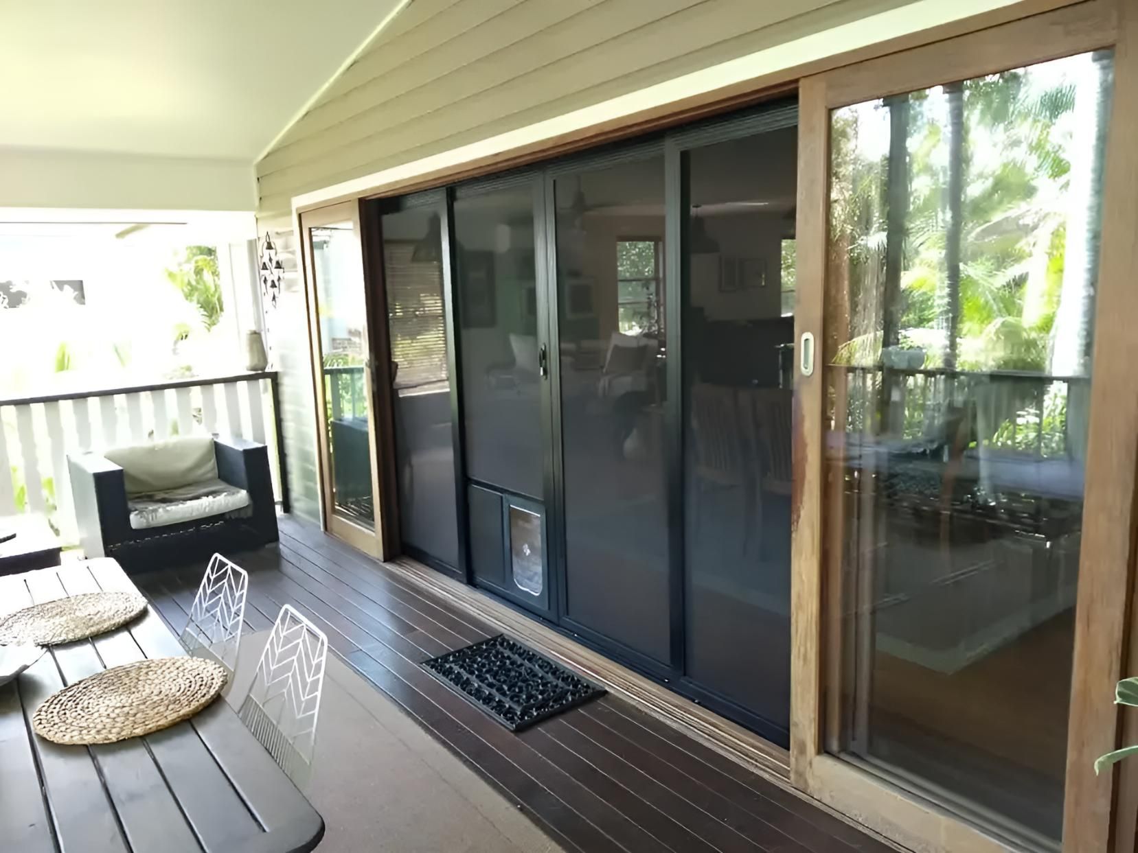 A Porch with Sliding Glass Doors and A Table and Chairs — Grainger Windows & Doors in Alstonville, NSW