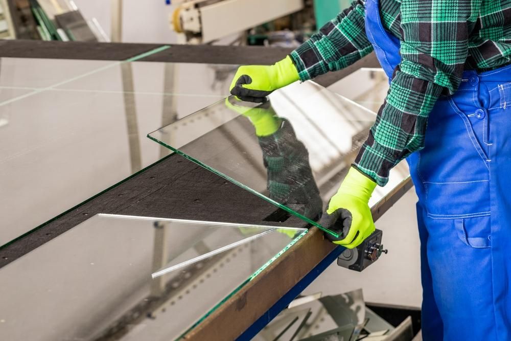 A Man Is Cutting a Piece of Glass in A Factory — Grainger Windows & Doors in Ballina, NSW
