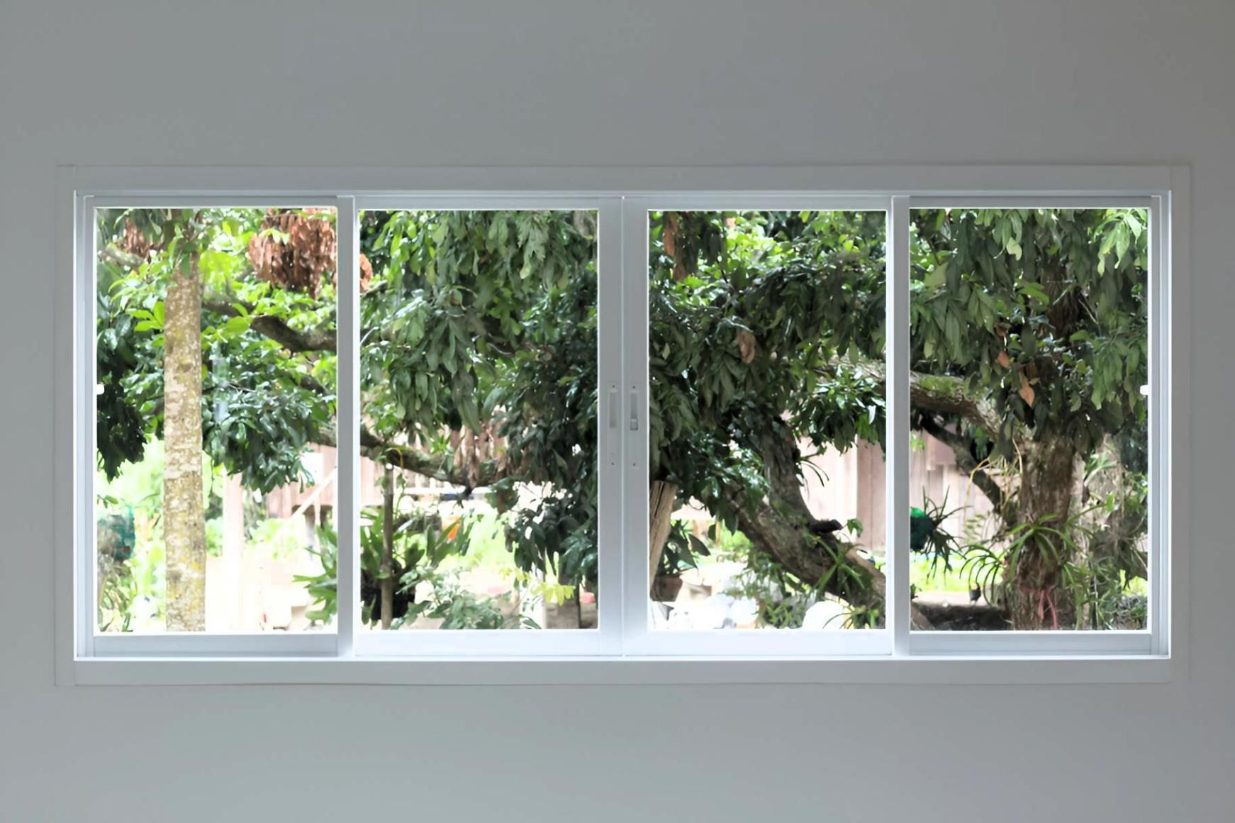 A Large Window with Sliding Glass Doors Looking out To a Tree — Grainger Windows & Doors in Ballina, NSW