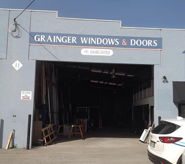 A White Car Is Parked in Front of A Building that Says Grainger Windows and Doors — Grainger Windows & Doors in Ballina, NSW