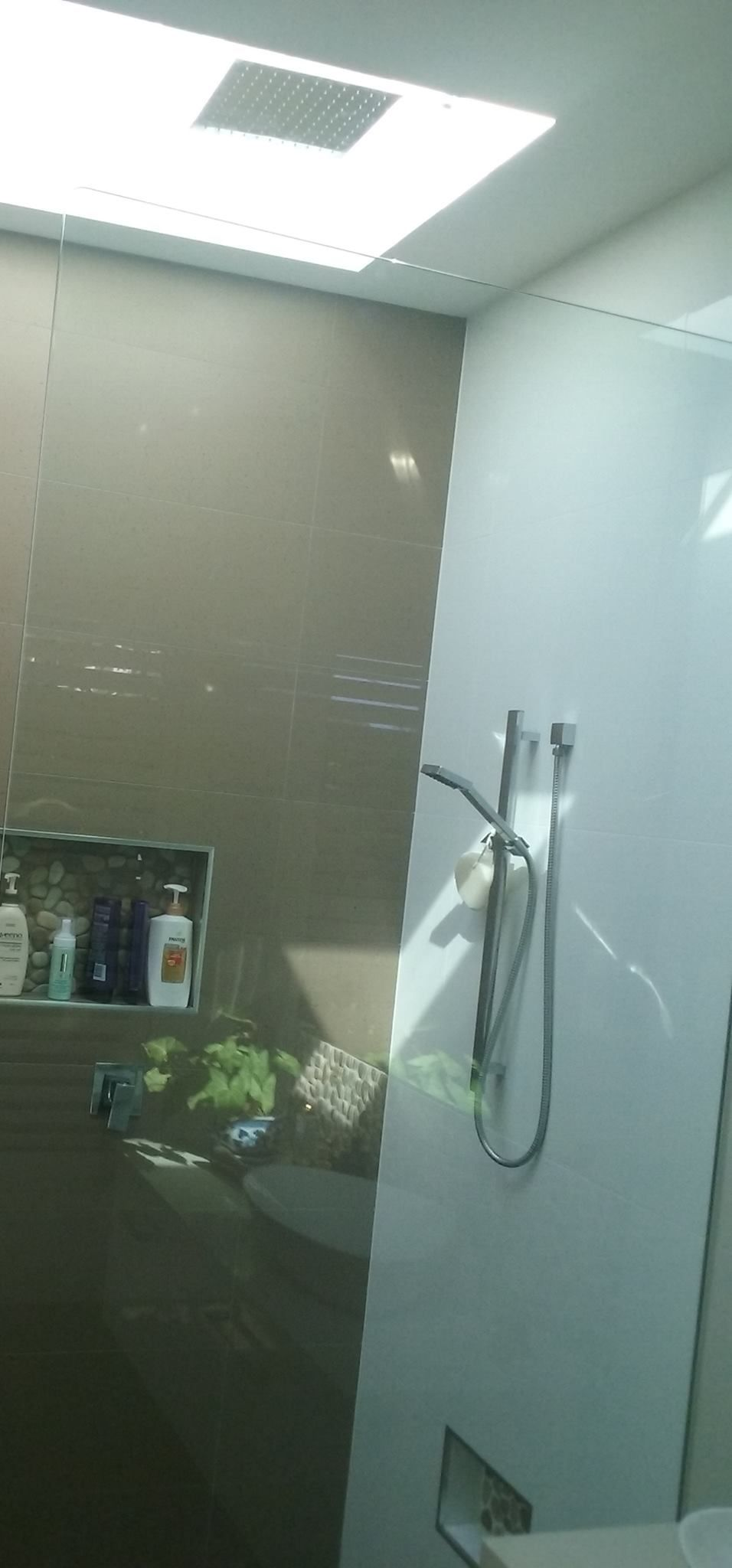 A modern bathroom with a glass shower door and overhead lighting.