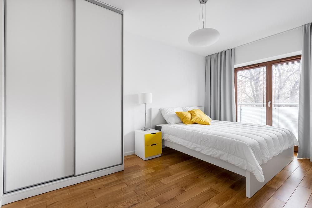 A Bedroom with A Bed, Nightstand, and Sliding Wardrobe — Grainger Windows & Doors in Ballina, NSW