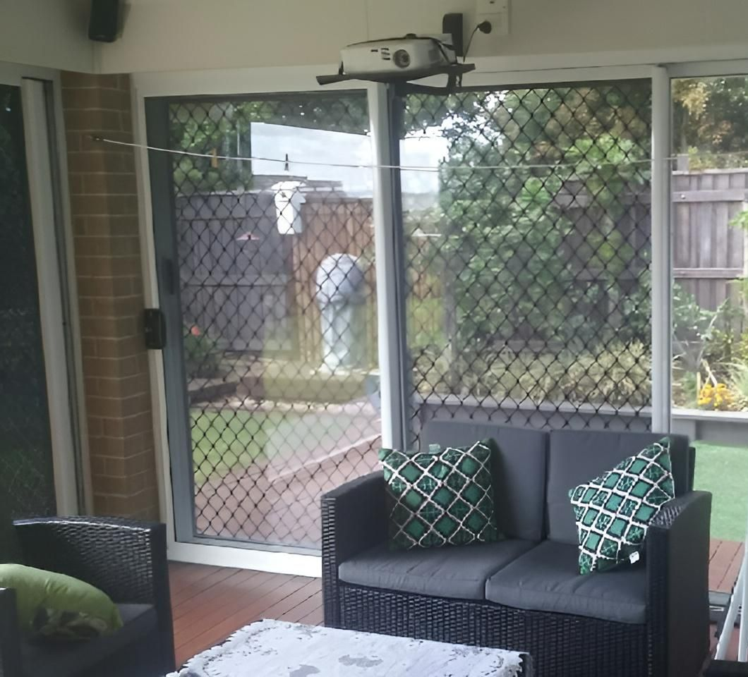 A Living Room with A Couch, Chair, Table and Sliding Glass Doors — Grainger Windows & Doors in Alstonville, NSW