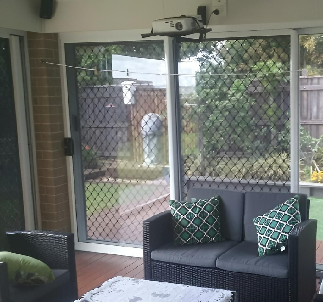 A Living Room with A Couch, Chair, Table and Sliding Glass Doors — Grainger Windows & Doors in Ballina, NSW